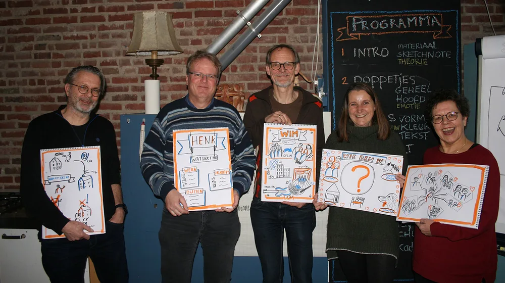 Vijf deelnemers laten trots hun eigen tekeningen zien na de workshop.