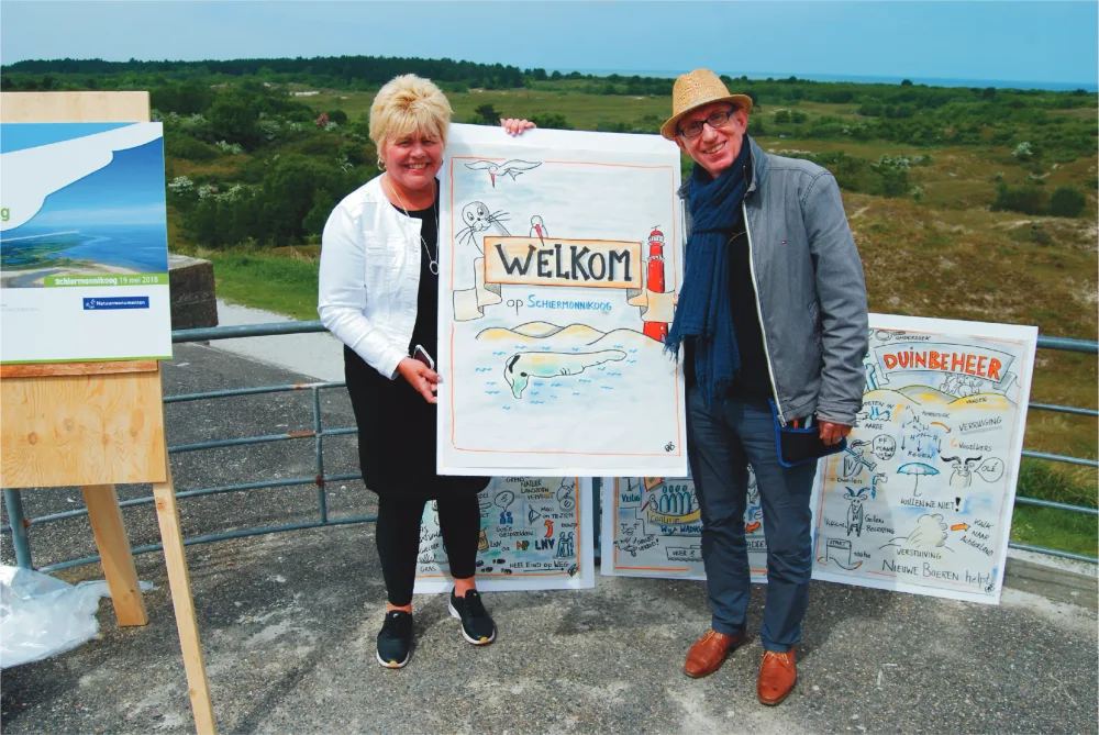 Burgemeester Ineke van Gent en Ron bij een getekende welkomstplaat.